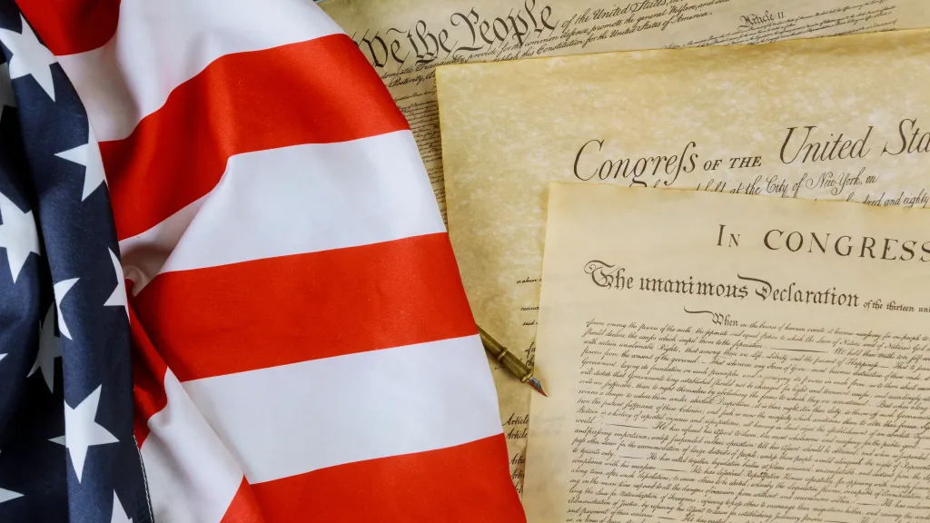 An American flag with a copy of the U.S. Constitution